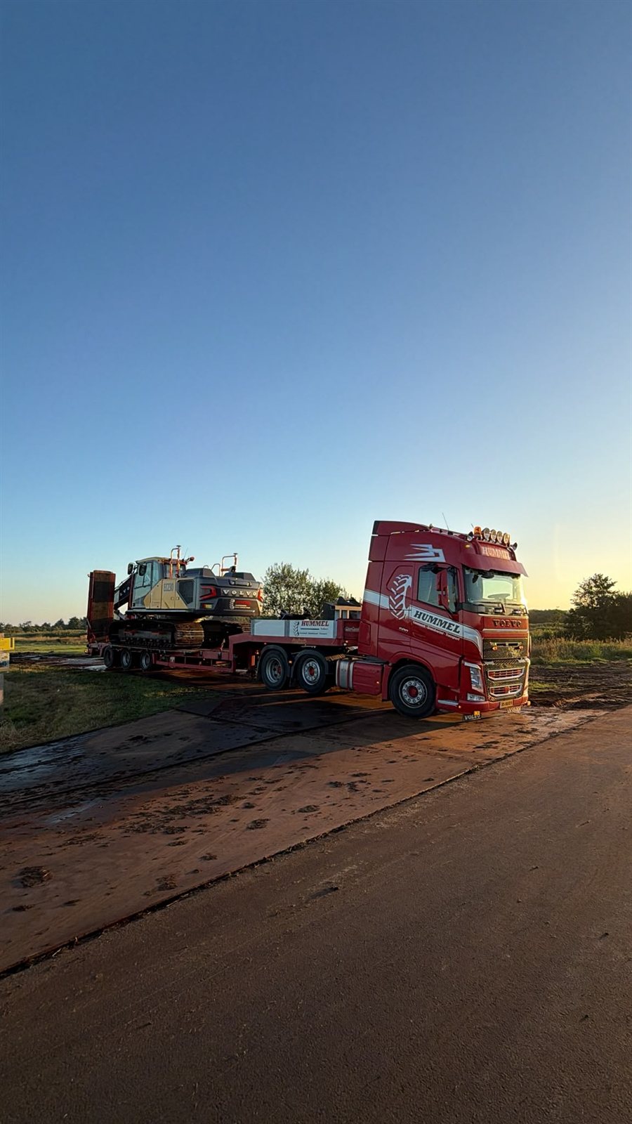 Dieplader met rupskraan in de avondzon