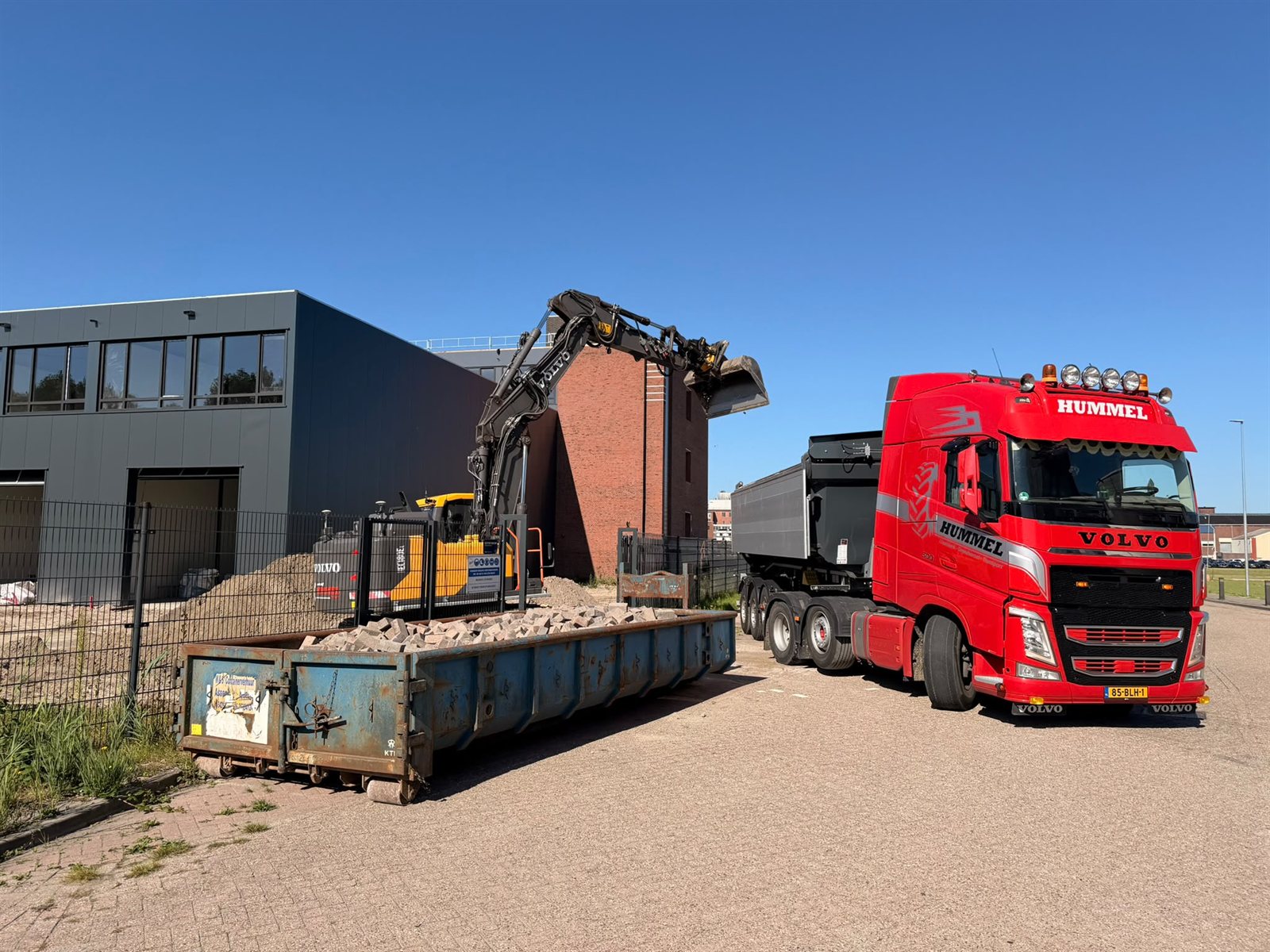 Kraan, container en kipper bij een bouwplaats