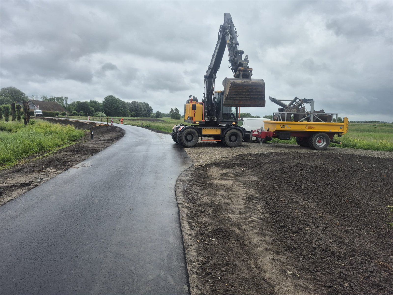 Mobiele kraan bij bermwerk langs een asfaltweg
