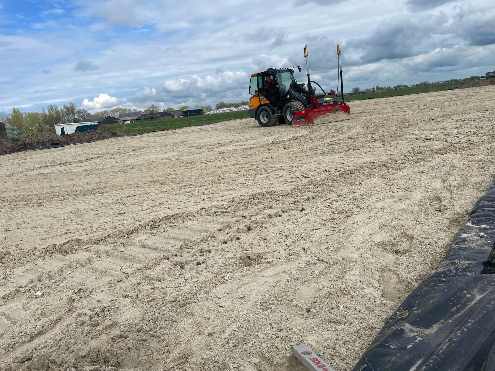Shovel met levelbak over het zandbed