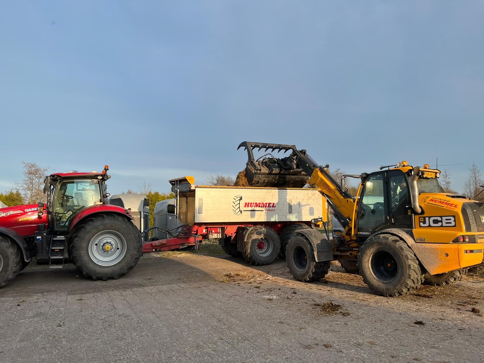 JCB-shovel laadt mest in de strooier achter de tractor
