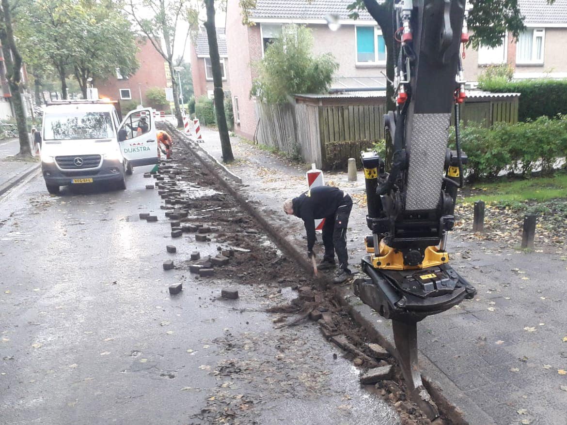 Kraan breekt straatwerk op in een woonstraat