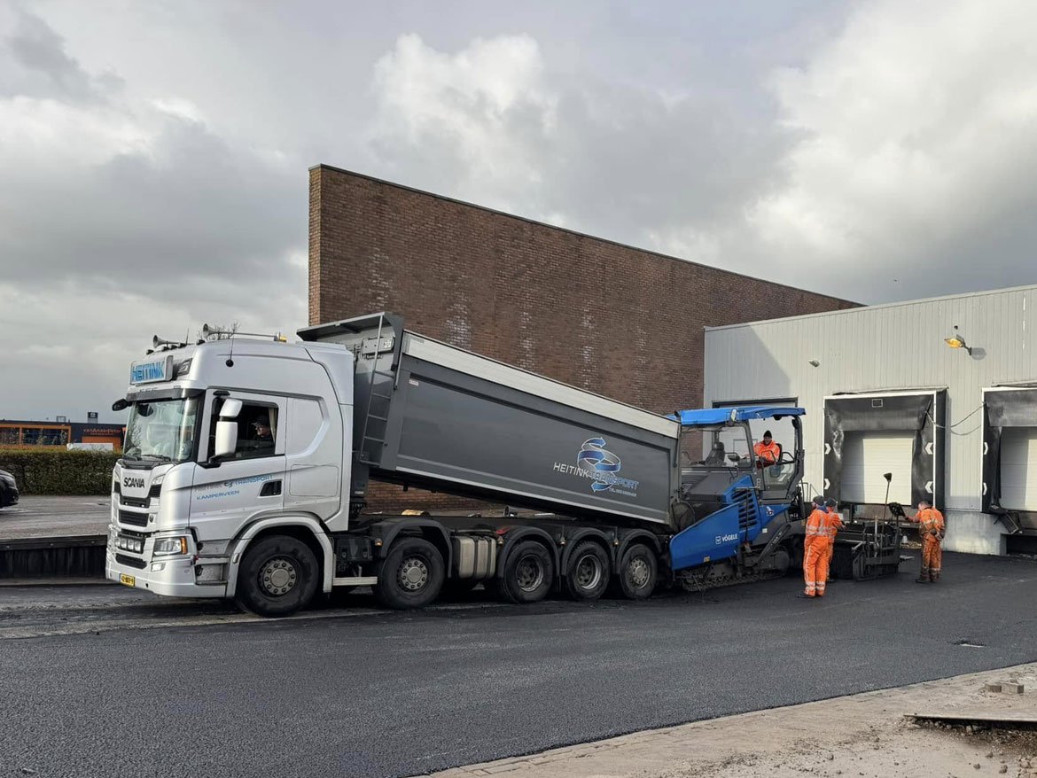 Vrachtwagen voert asfalt aan voor de asfaltspreidmachine