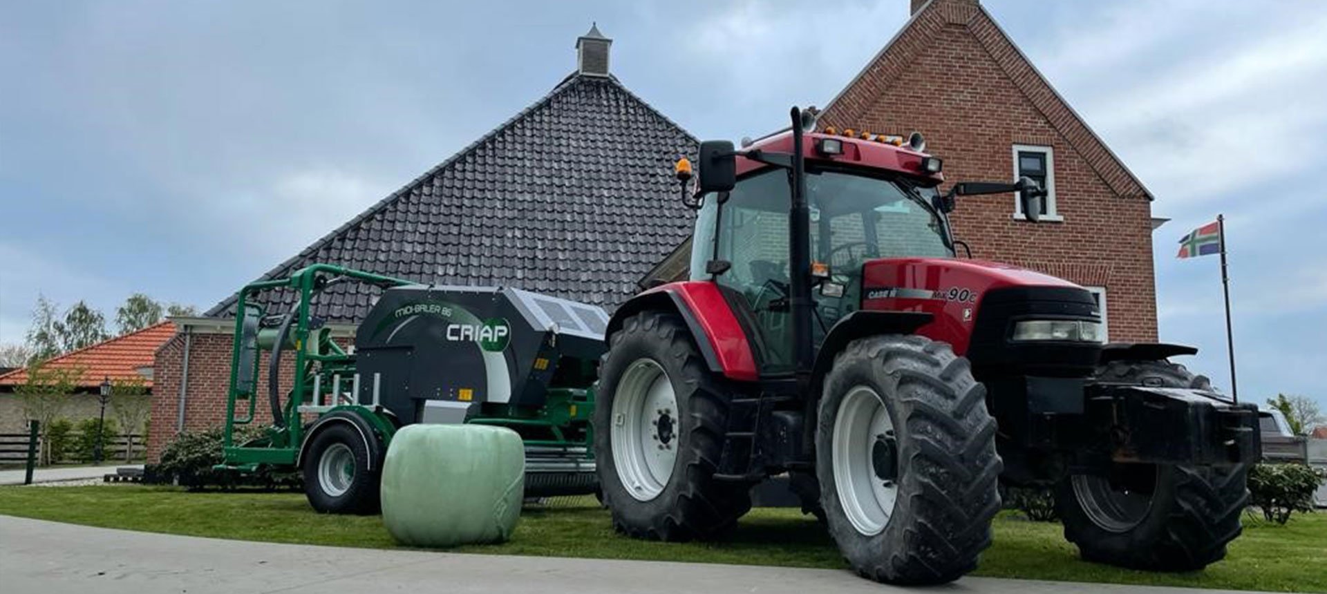 Tractor met Criap pers-wikkelcombinatie en een gewikkelde baal voor een boerderij