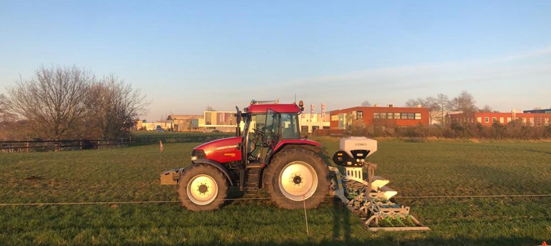 Tractor zaait grasland door bij avondlicht