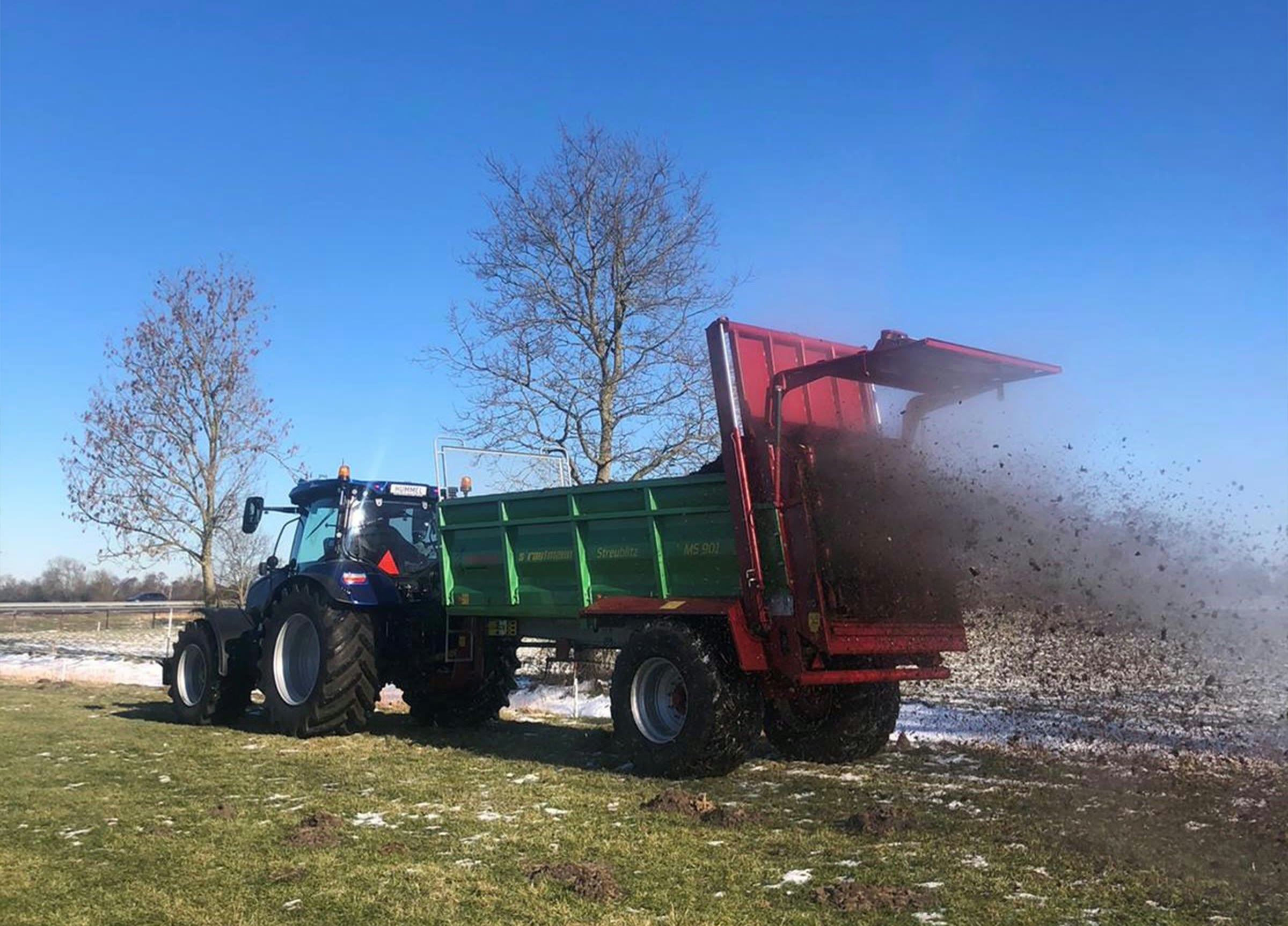 Tractor strooit vaste mest over het land