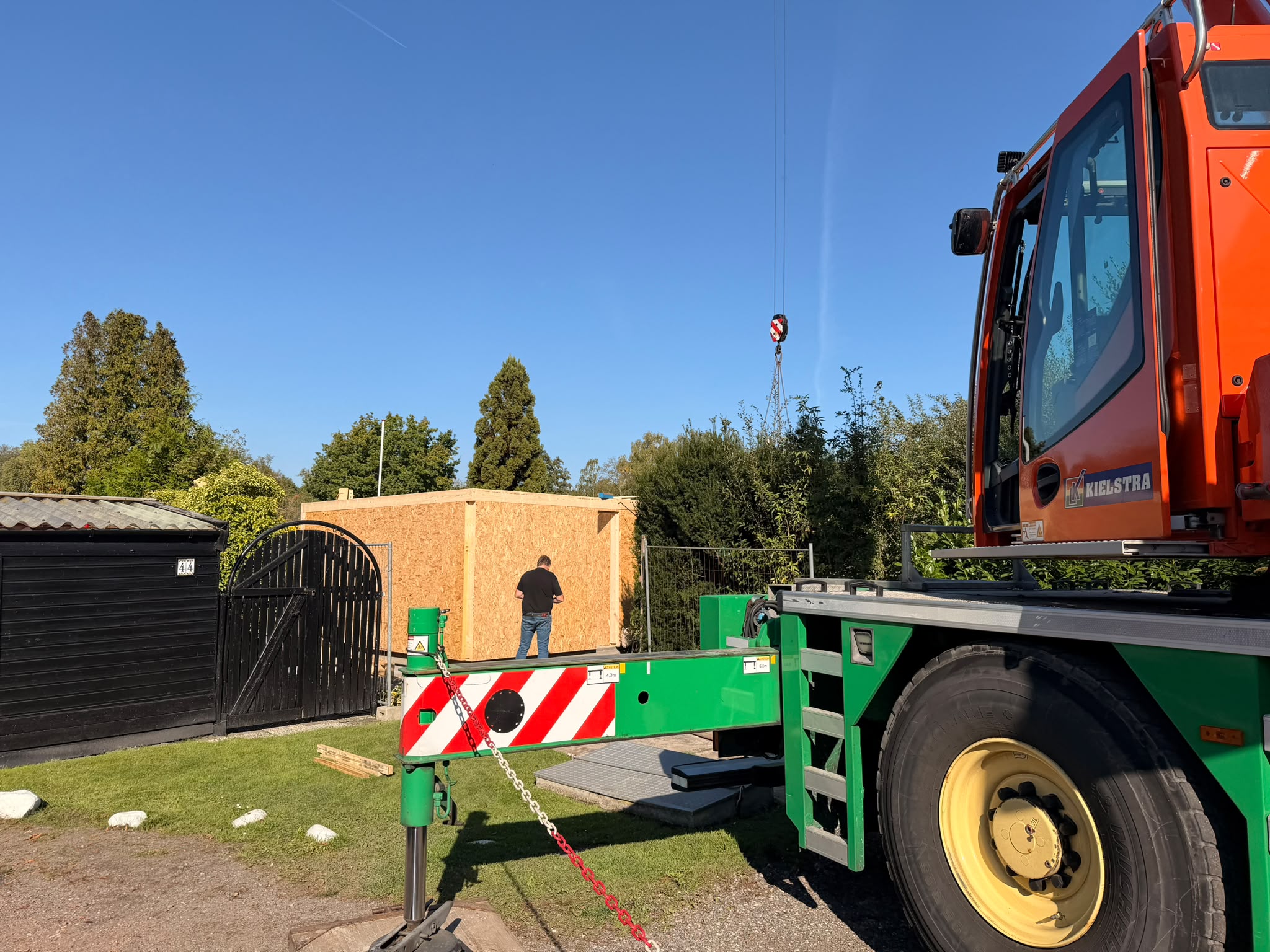 De mobiele kraan staat opgesteld om de prefab wandelementen te plaatsen