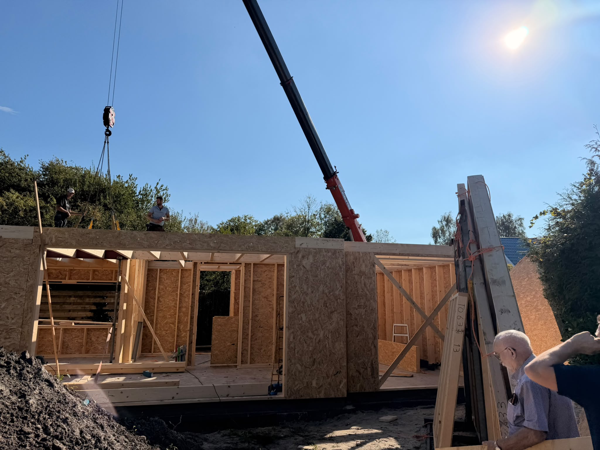 Een prefab wandelement hangt aan de kraan en wordt op zijn plek gezet